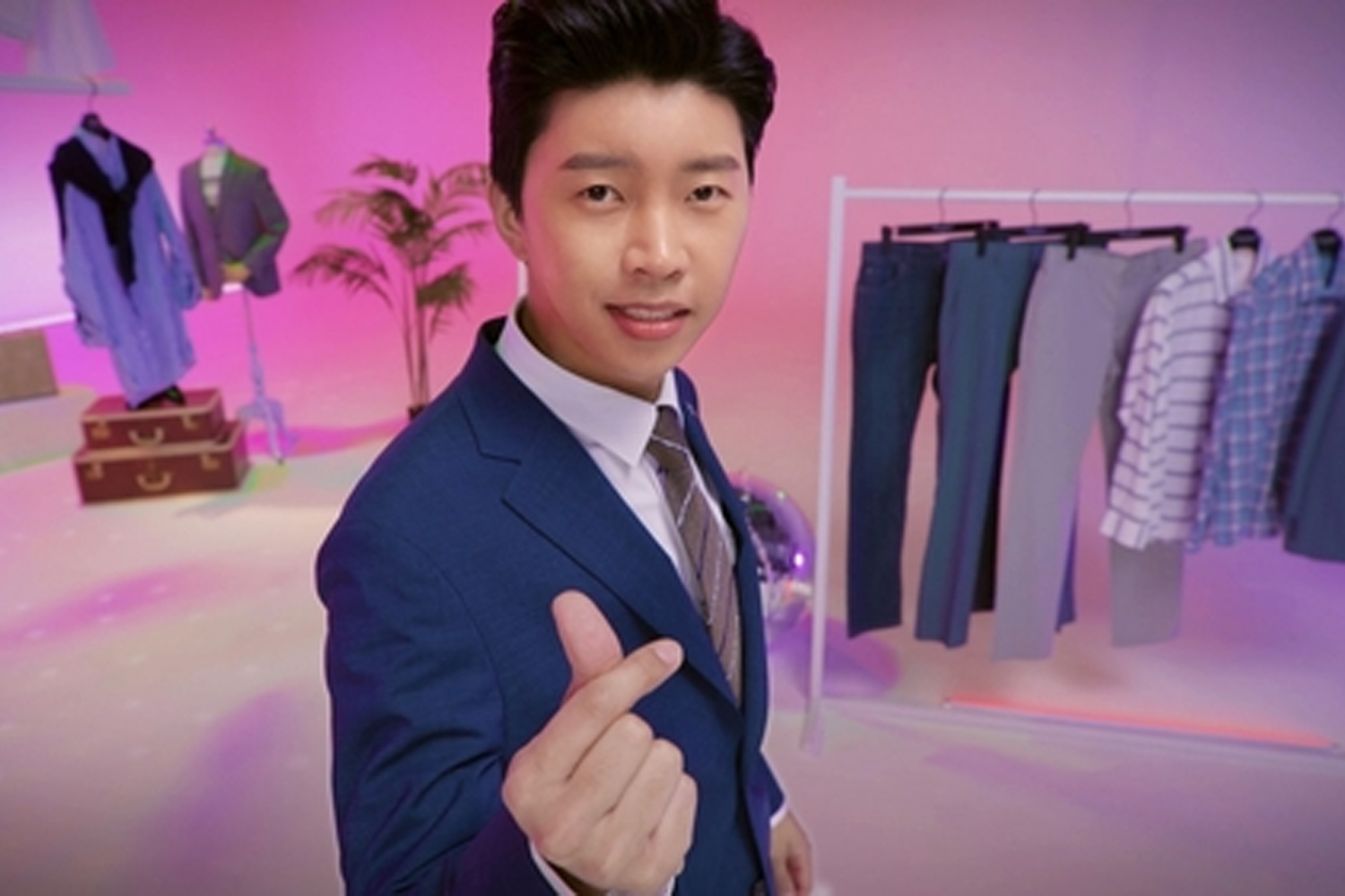 西裝品牌形象廣告，模特穿著藍色西裝，背景是粉紅色和紫色的搭配。