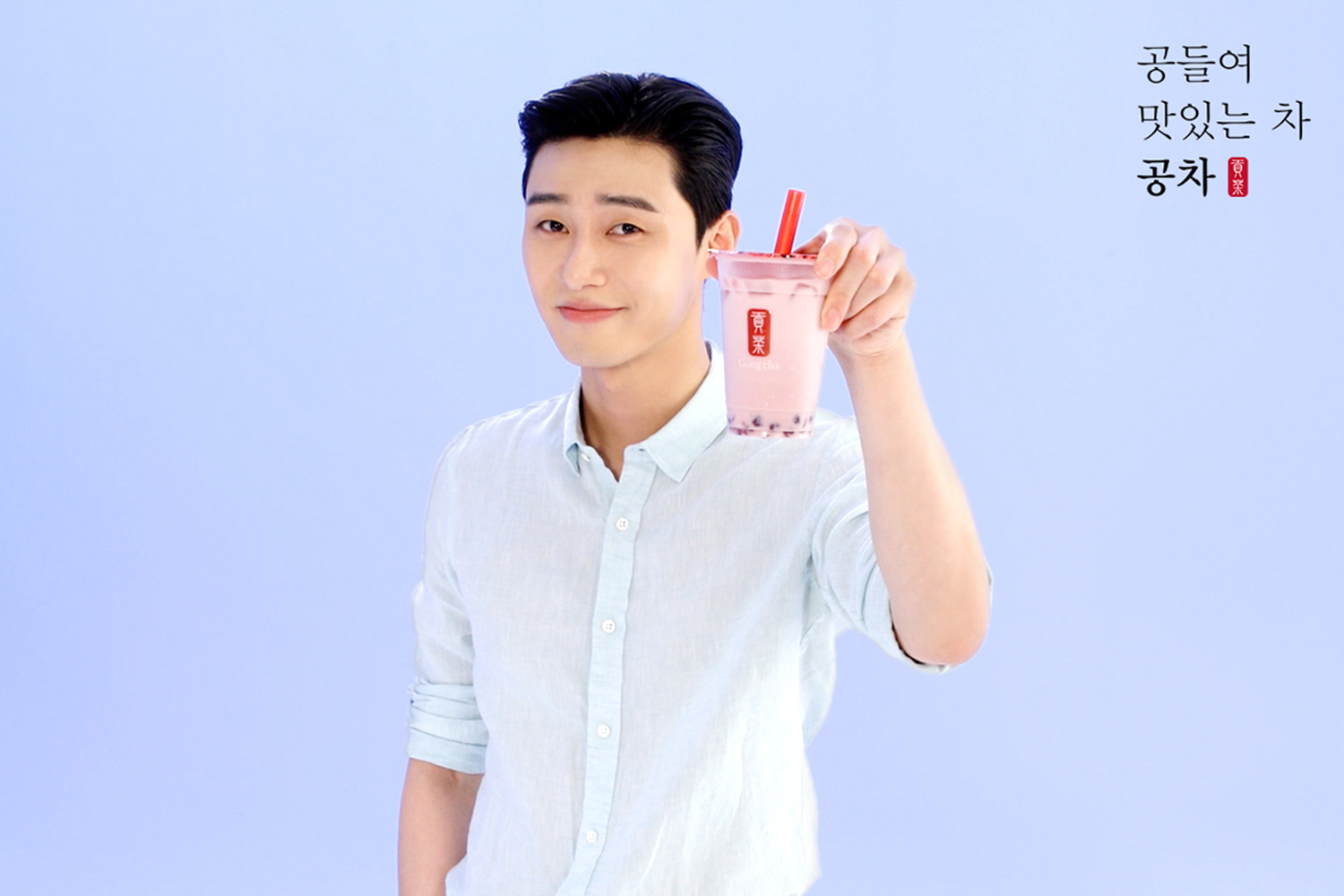 台灣貢茶廣告形象，背景是淡藍色，模特拿著一杯淡粉色的飲品。