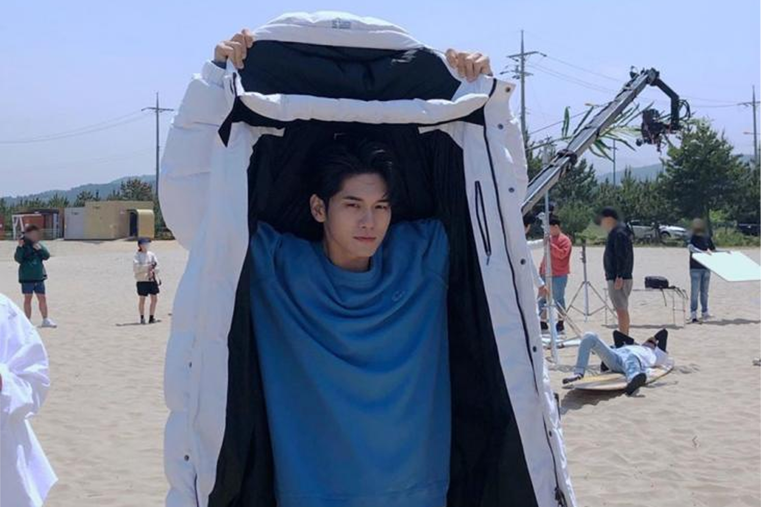 藝人邕聖祐在户外，穿著白色襯衫，外面搭配黑色大衣，舉手致意