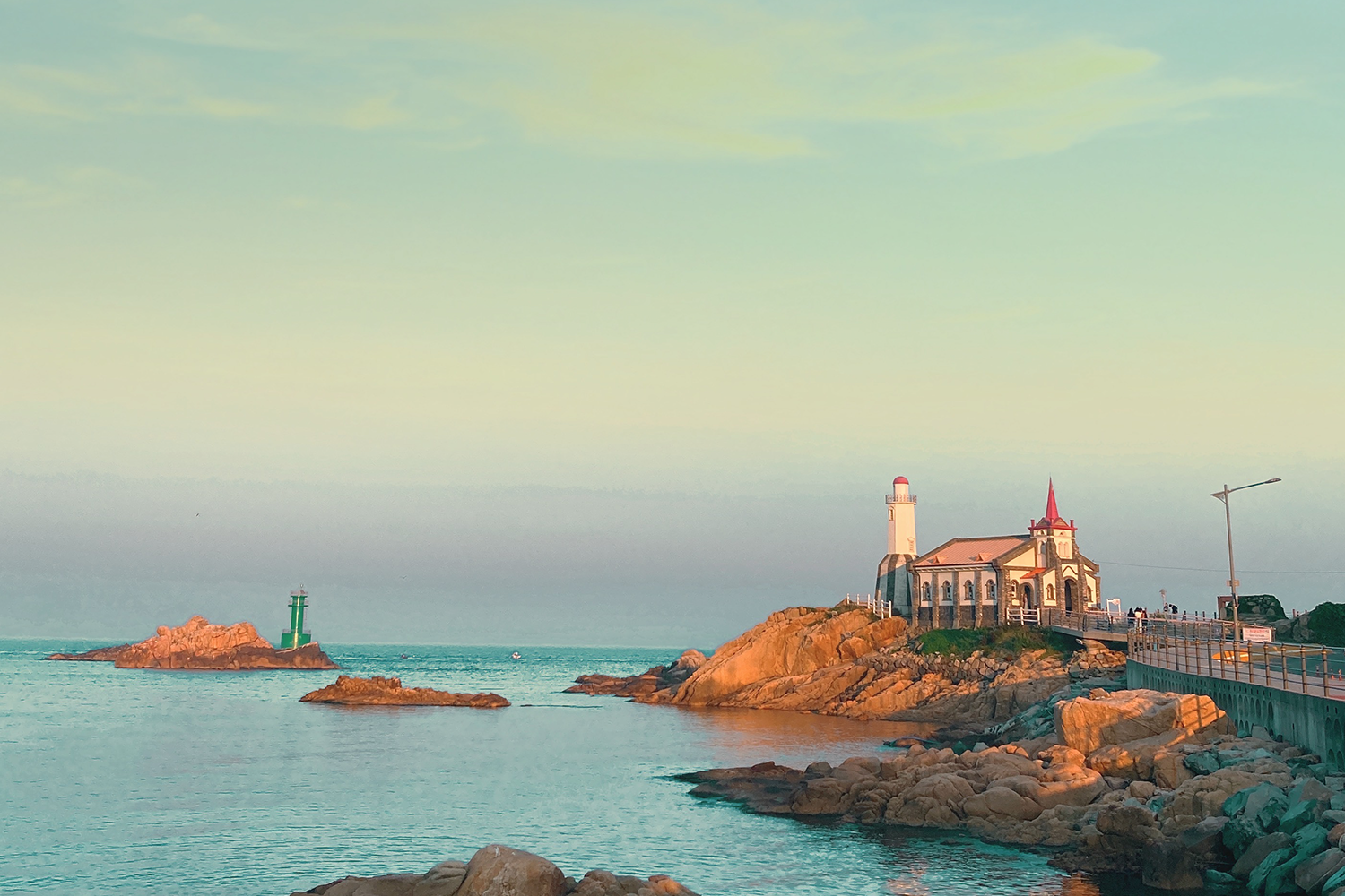 以黃昏時刻拍攝的竹城聖堂與燈塔，溫暖的色調勾勒出恬靜的海岸風光。