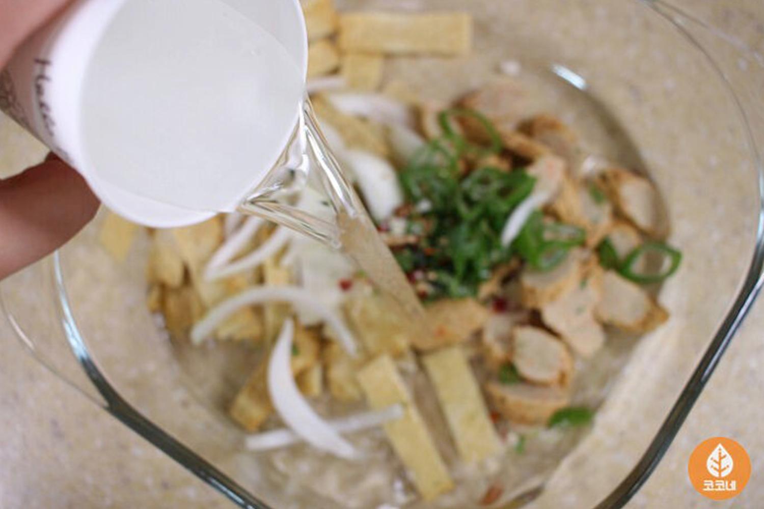 在碗中加入水，所有食材包括魚糕、大葱及洋葱都準備好，只需簡單步驟就能製作快速美味的韓國魚糕湯，只需加水並進行加熱。