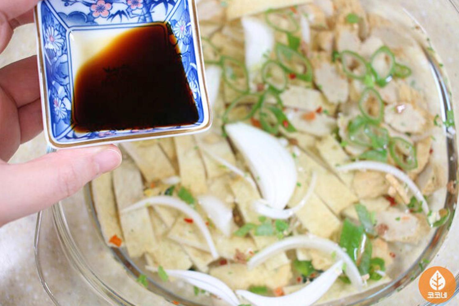 圖片展示瞭如何在韓國魚糕湯中加入適量的豉油,以增強湯汁的美味,成為一道令人暖心的韓國魚糕湯。在這個步驟中,豉油的調整能使味道更加豐富。