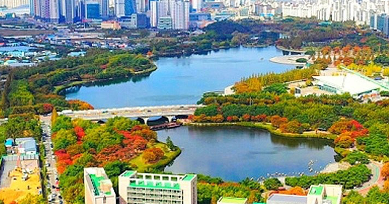 展示韓國一山新公園的俯瞰景觀，有湖泊和五顏六色的樹木