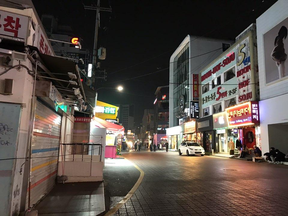首尔弘大购物区和停车场街交汇处夜景，地面铺满暖色调砖石，街道空旷。