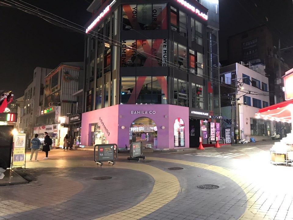 首尔弘大道灯火通明的街区，人流稀少，店面关闭。