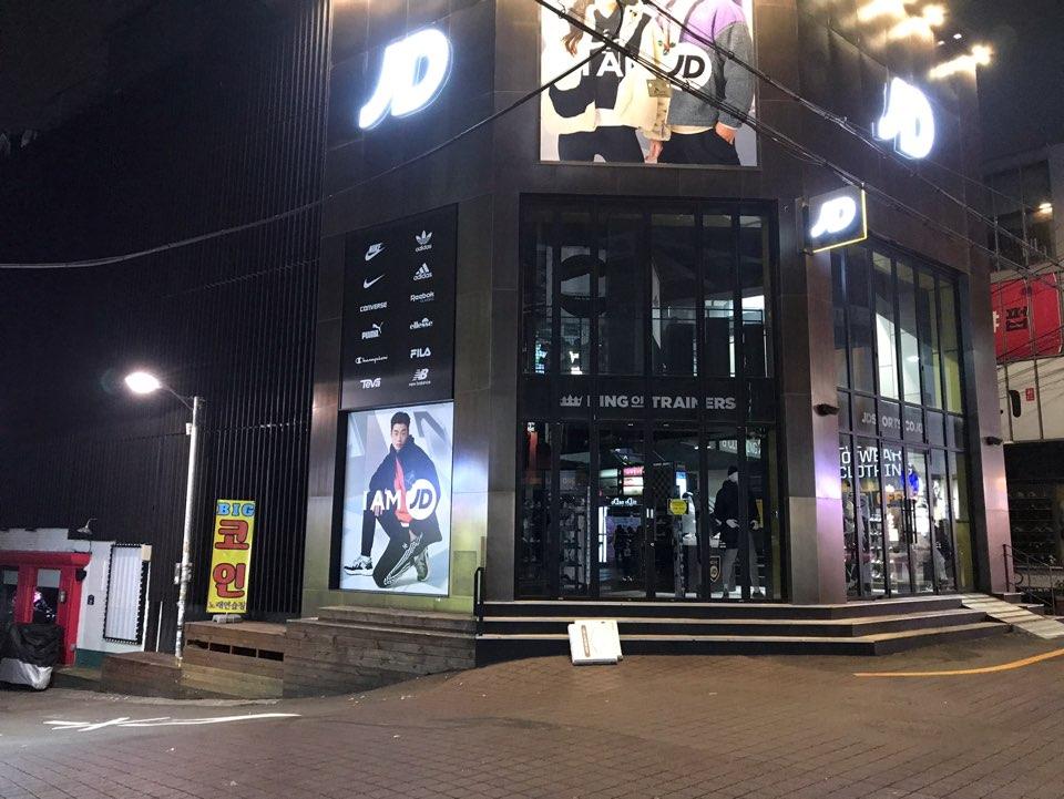 首尔弘大商店夜晚，灯箱广告突出，行人较少，环境静谧。