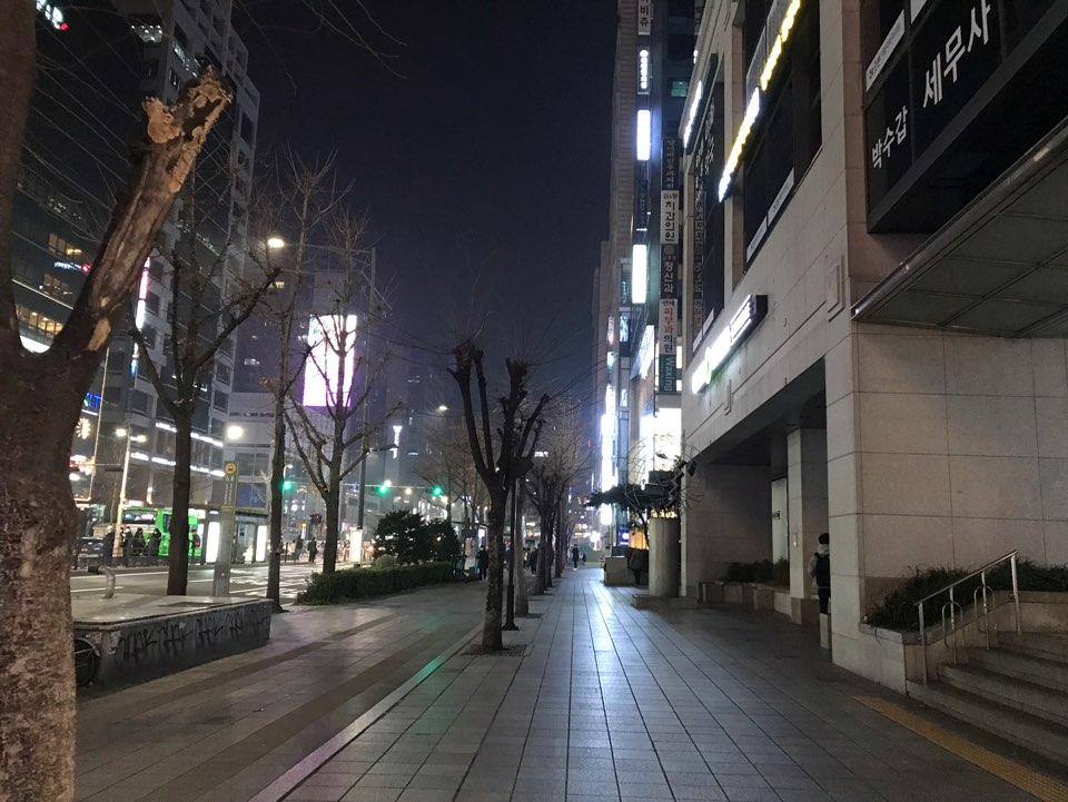 首尔弘大道主干路夜景，两旁高楼大厦，行人稀少。