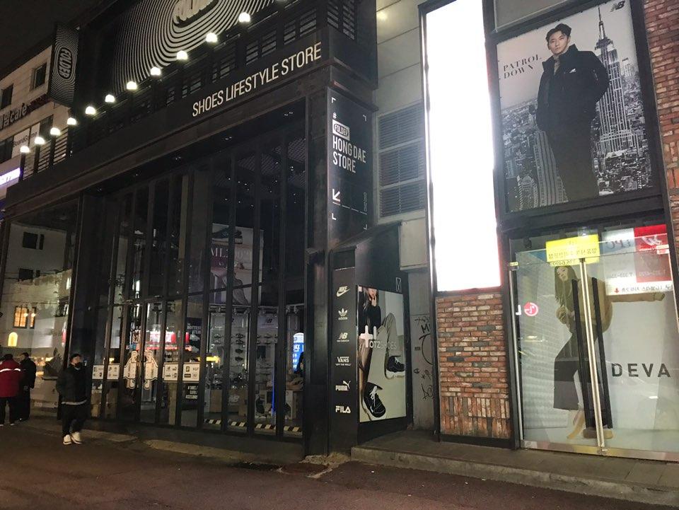 首尔弘大时尚店铺夜色，顾客稀少，玻璃门窗透出室内光线。