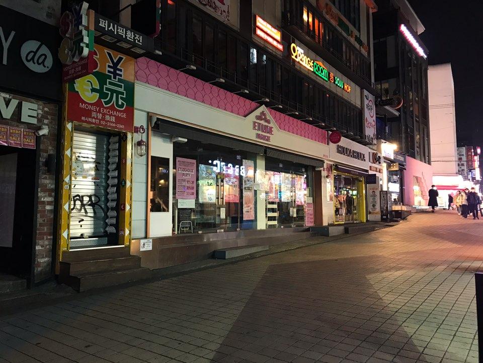 首尔弘大街头商店夜间景观，鲜艳的招牌灯光，行人极少。