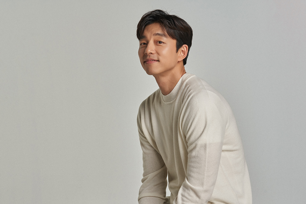 室內環境中一位穿著米色毛衣的男性，坐在椅子上展示自信與成熟的姿態