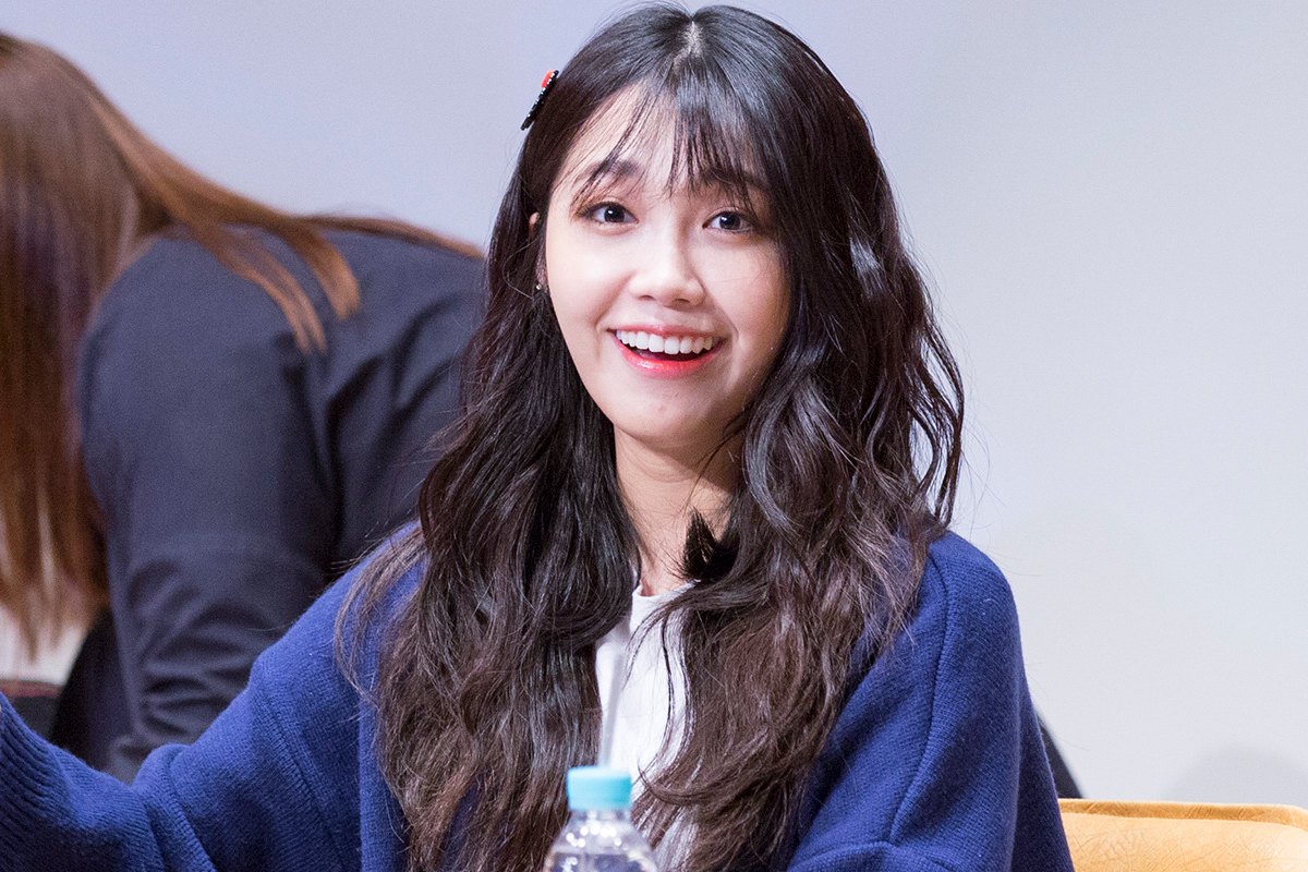 室內場景，一名穿著深藍色針織衫的女性坐在桌子旁，展現自然美麗的神情