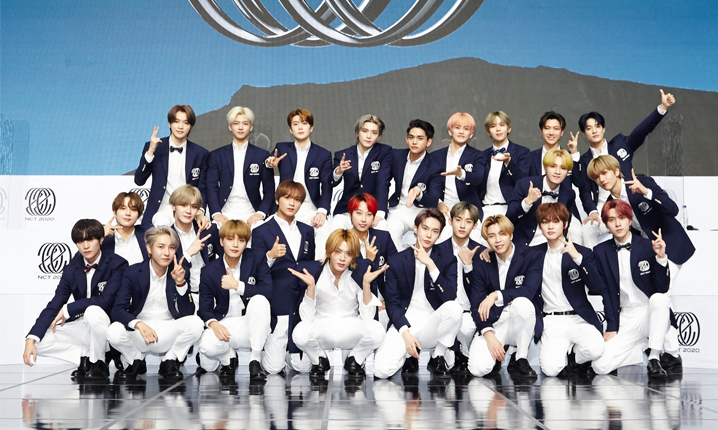 韓國男團NCT成員羣體合影於舞台上，穿著正式服裝