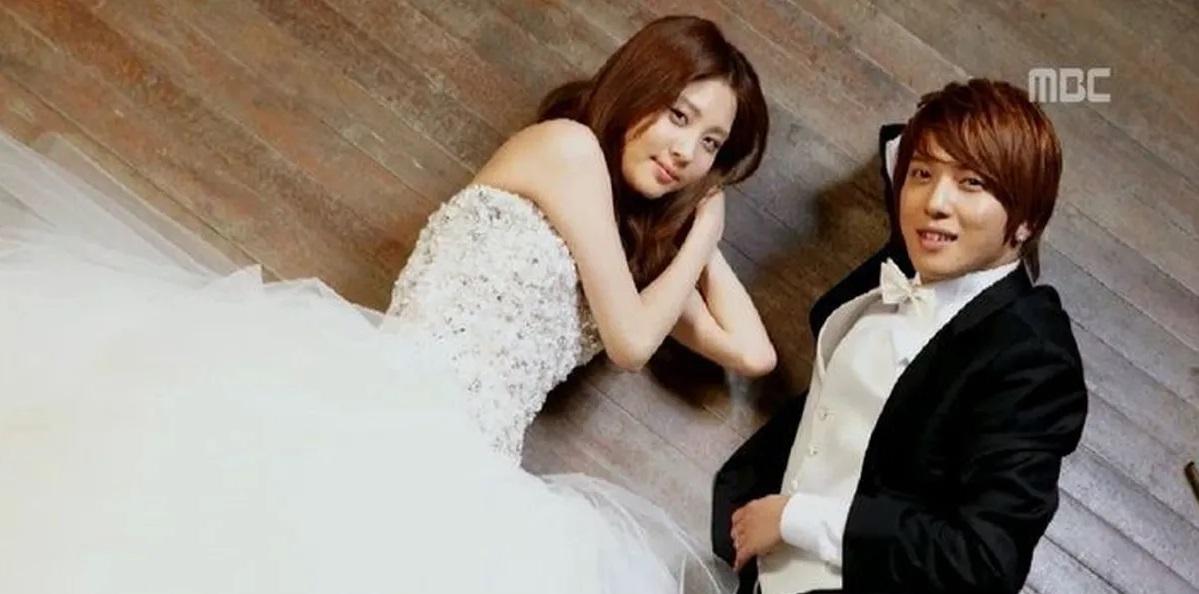 คู่หนุ่มสาวใส่ชุดเจ้าสาวและเจ้าบ่าว นอนอยู่บนพื้นไม้ โทนภาพโรแมนติก