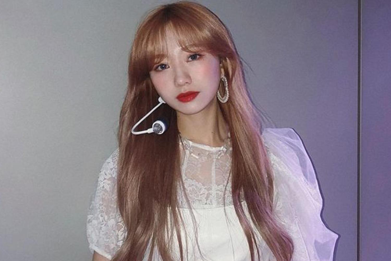 Lovelyz成員，身穿白色蕾絲裙，配戴耳麥，準備在舞台上表演。