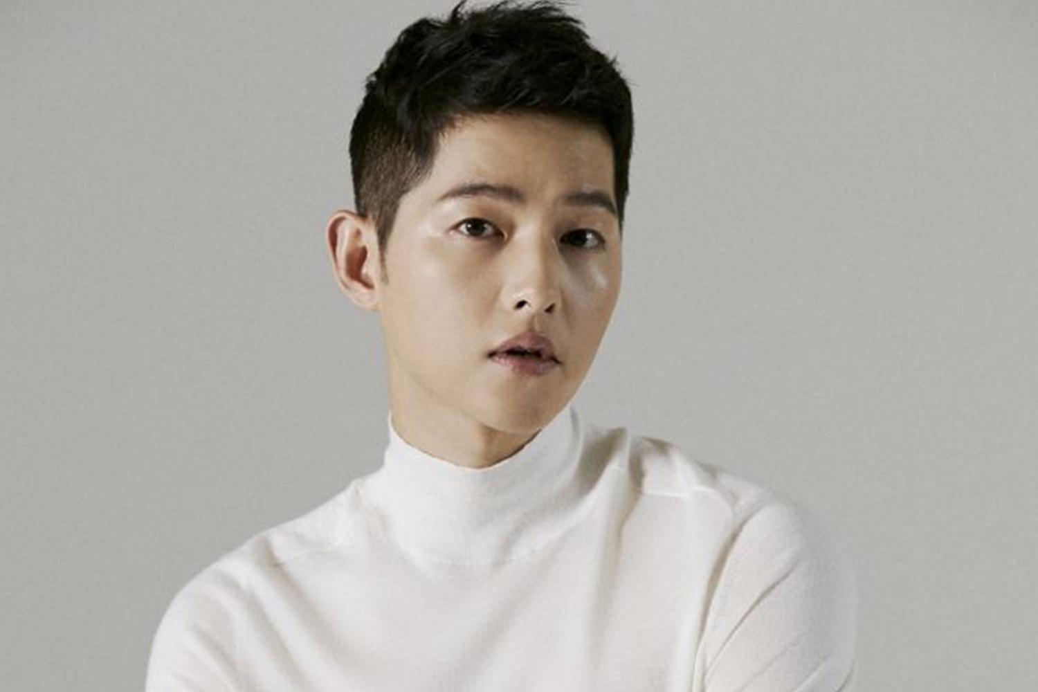 大田市出身的韓流明星，穿著白色高領毛衣，面帶微笑，背景是簡單的灰色。