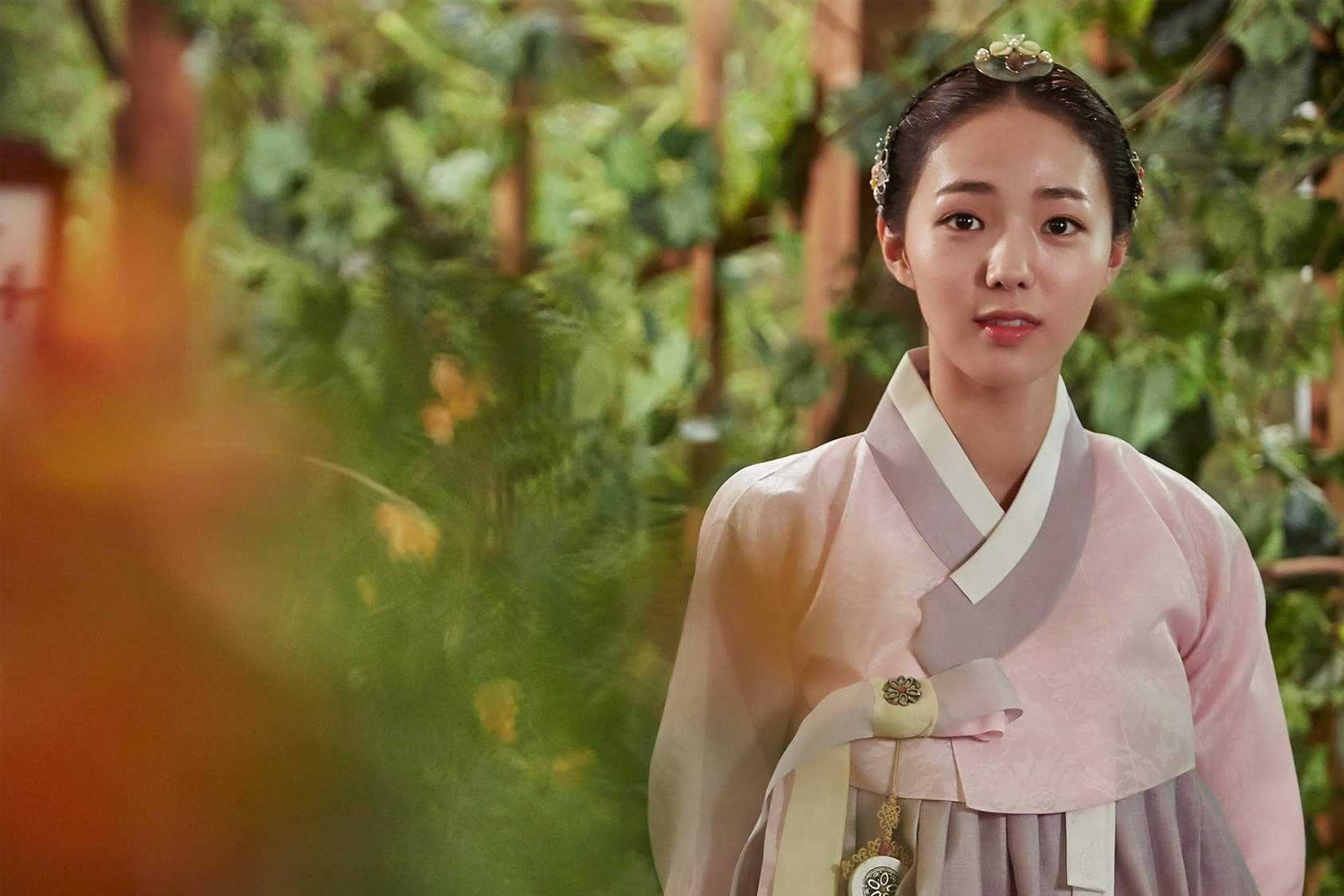 ภาพนางเอกหญิงในฮันบกสีชมพูนุ่มนวลจากซีรีส์เกาหลี Mr. Queen ฉากที่แสดงกลางป่า