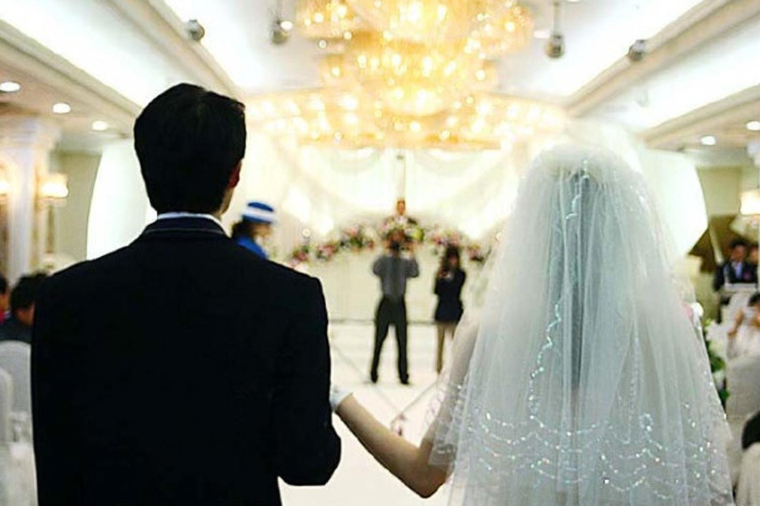 ภาพบรรยากาศในงานแต่งงานใต้แสงโคมไฟระยิบระยับพร้อมเจ้าบ่าวเจ้าสาวเดินเข้าสู่พิธี