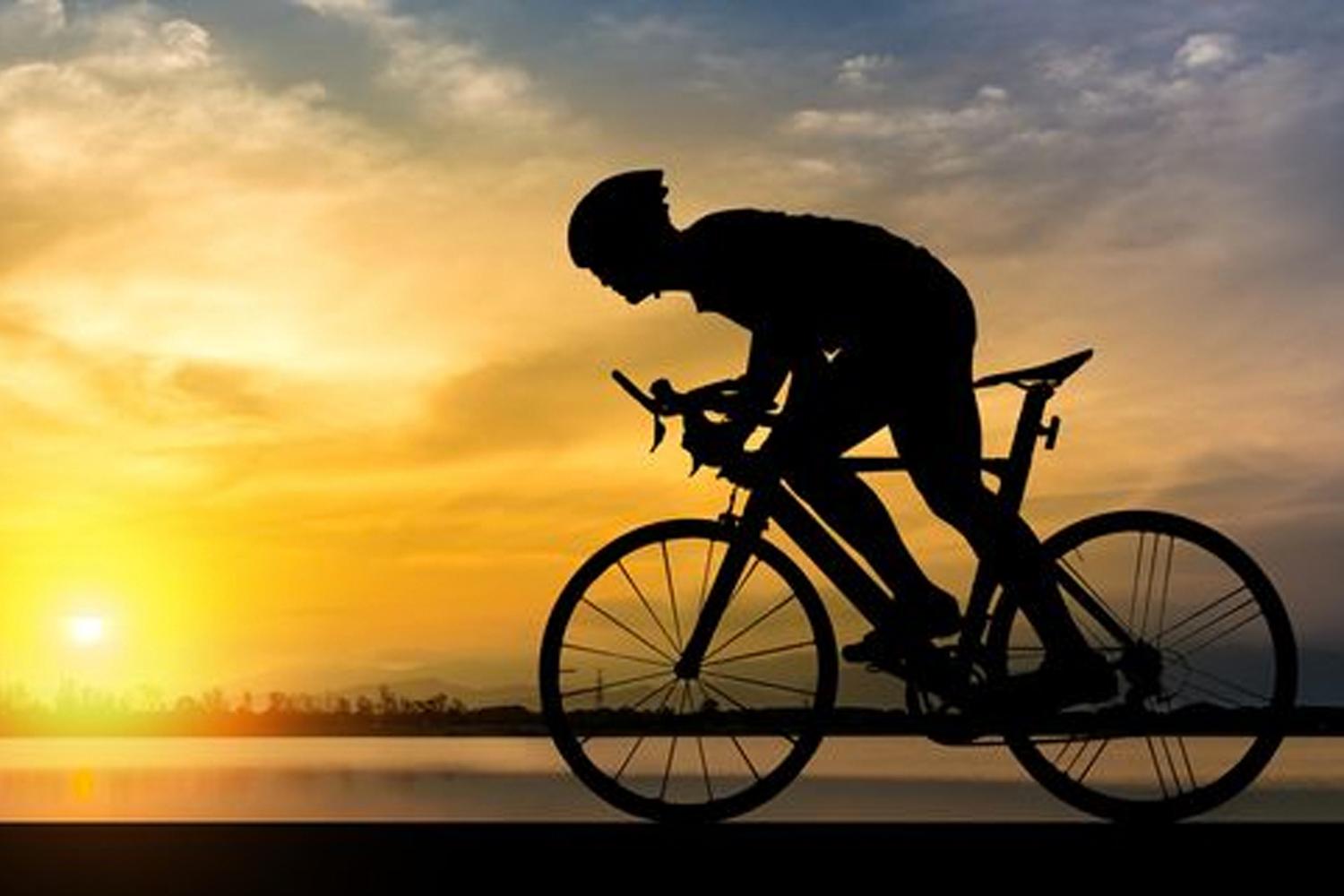 ภาพคนปั่นจักรยานใต้แสงอาทิตย์ตกดินแสดงให้เห็นถึงการออกกำลังกายและอิสระ
