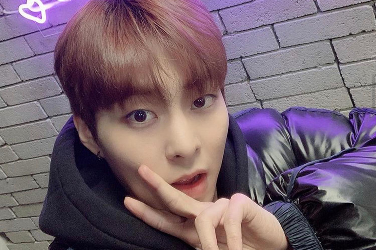 EXO 成員 XIUMIN 戴著帽子自拍，背景是一個紫色調的牆壁。