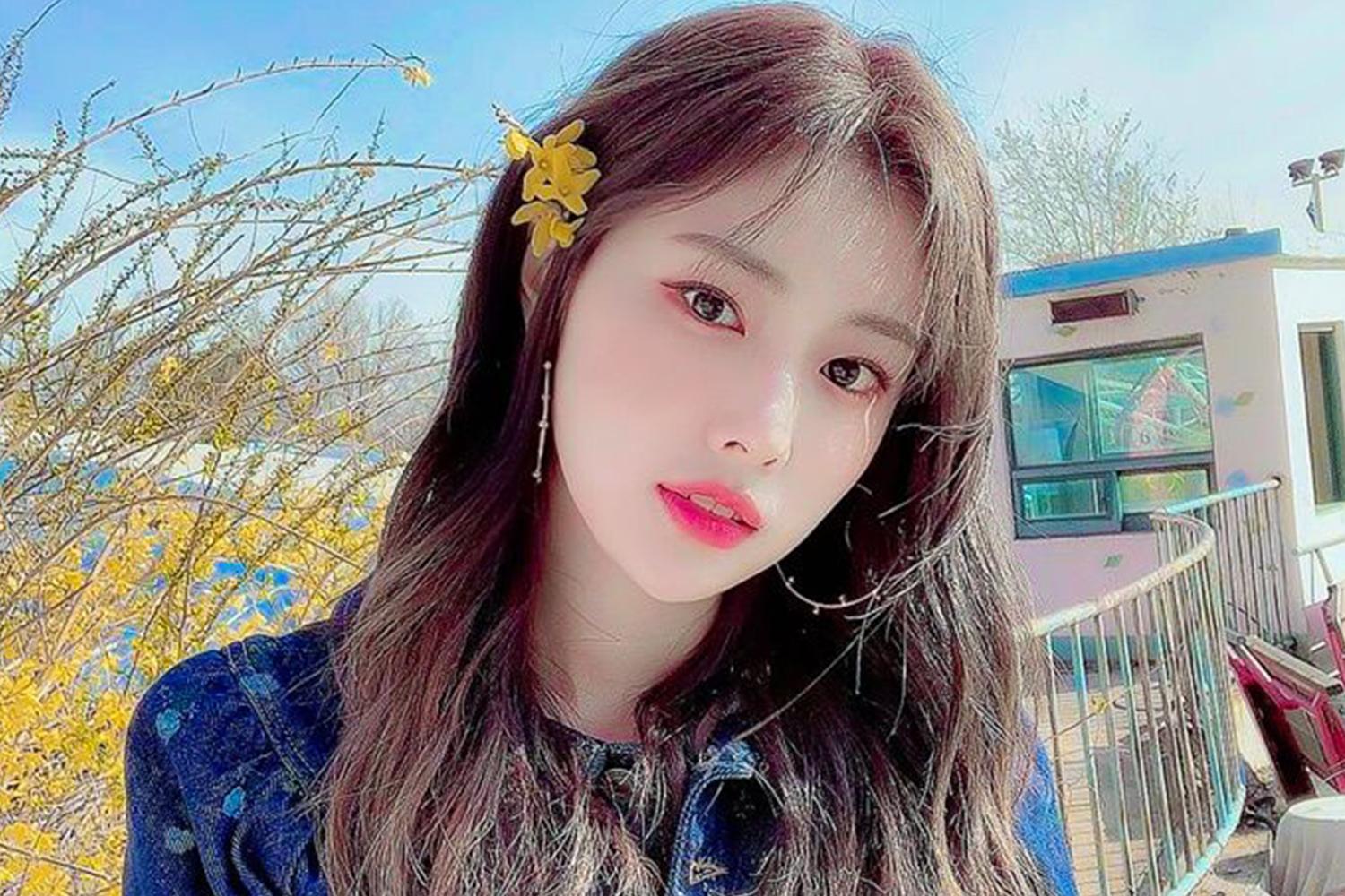 IZ*ONE 的成員姜惠元在户外，背景是一個陽光明媚的日子，她穿著牛仔外套。