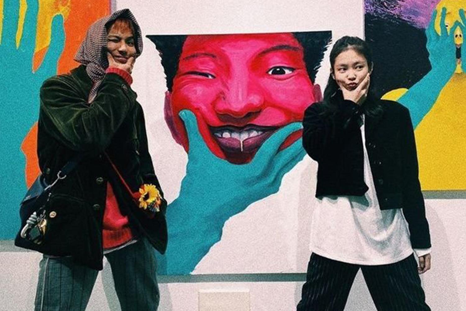 一對人在色彩豐富的畫展中，展示出時髦的服裝搭配和藝術氛圍。