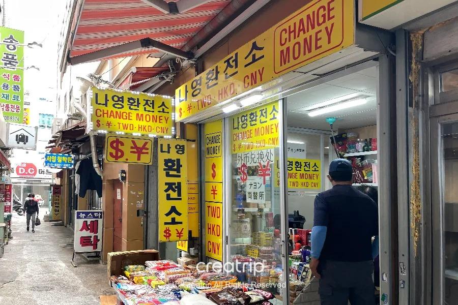釜山西面的老奶奶換錢所店面入口，標示提供多種貨幣的兌換選擇，吸引熟悉的顧客。