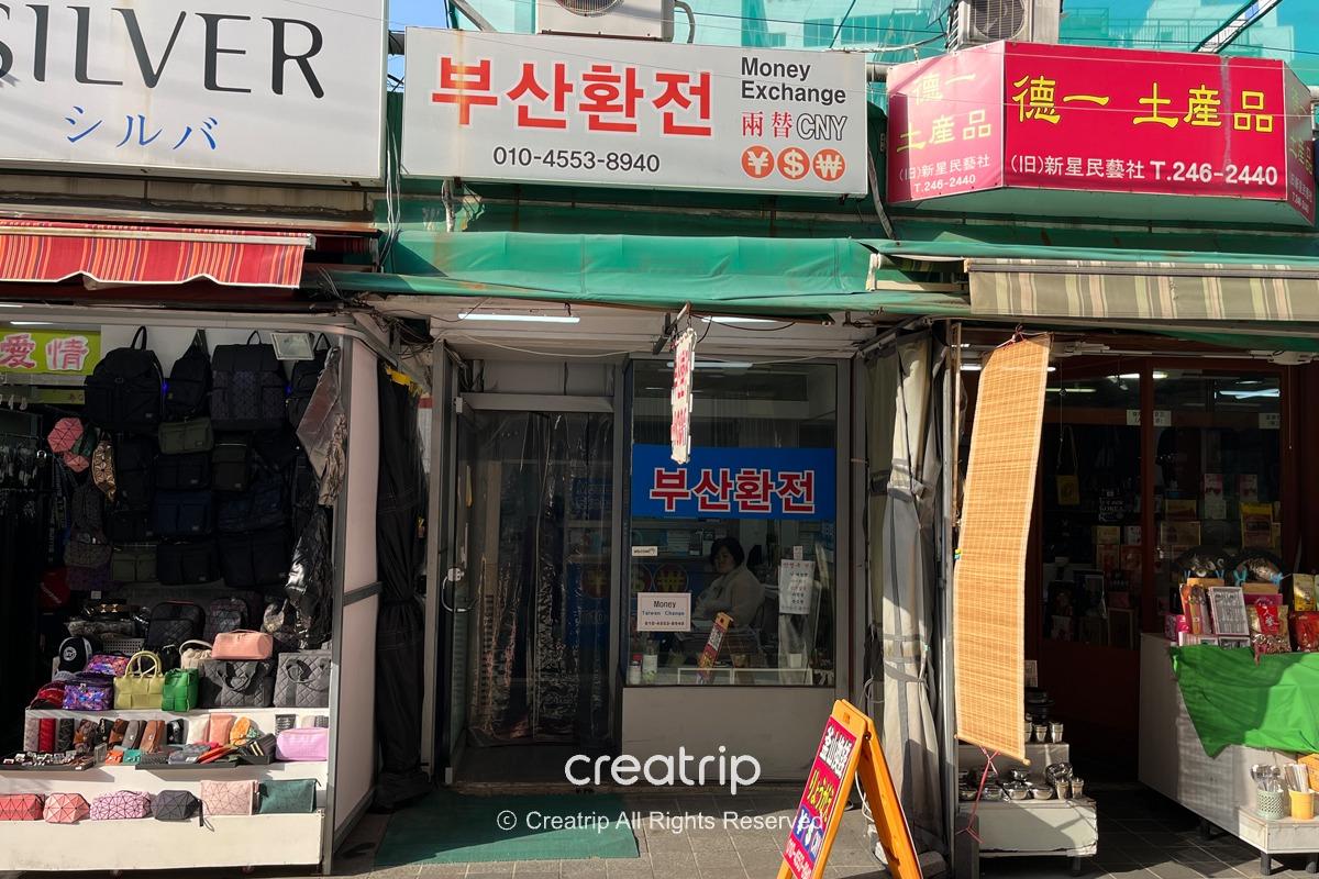 釜山換錢所店面外觀，展示多種貨幣兌換服務的信息板，方便旅客在南浦洞兌換韓元。