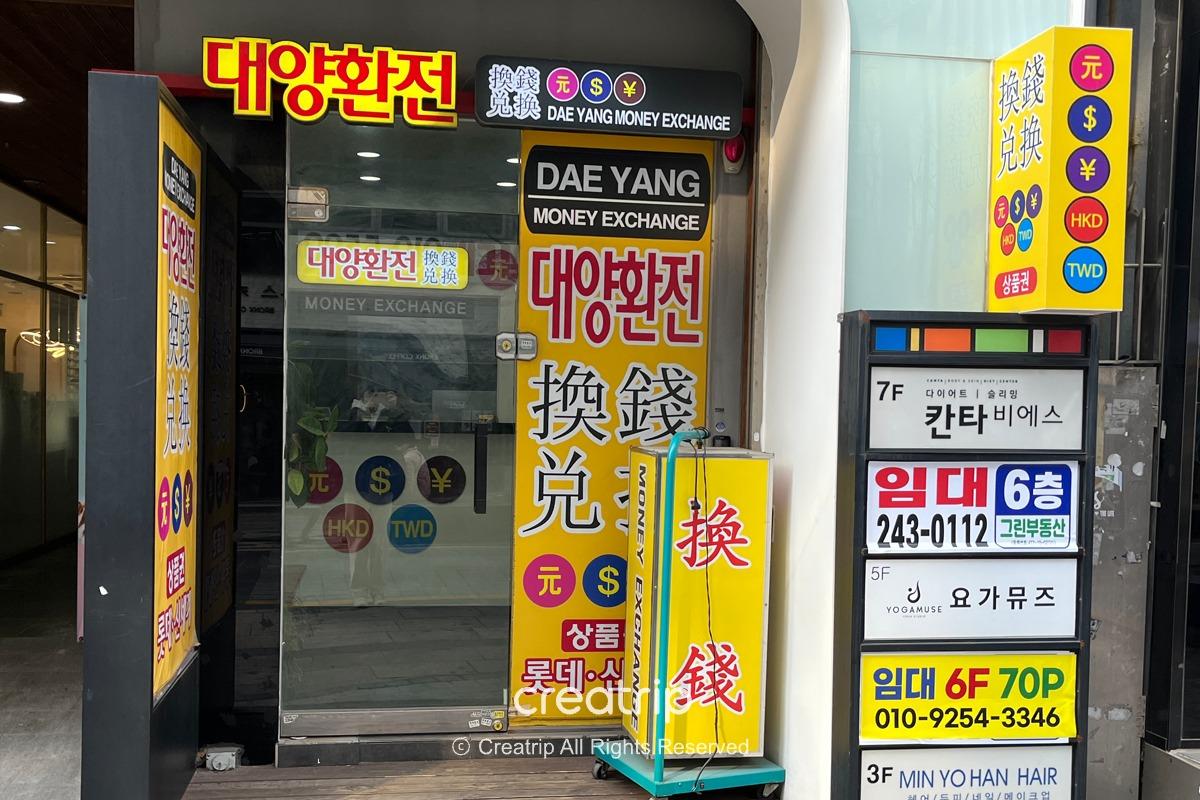 釜山太陽換錢所的店面，展示多彩醒目的貨幣兌換標示，吸引旅客在商圈內進行貨幣兌換。