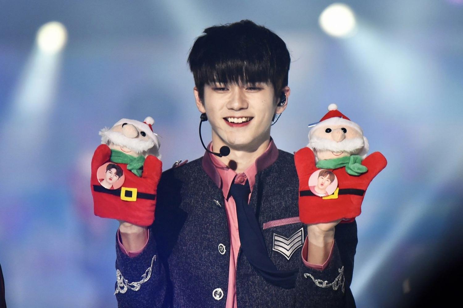 韓國男藝人手握兩個聖誕老人手偶，在舞台上展現活潑可愛的一面。