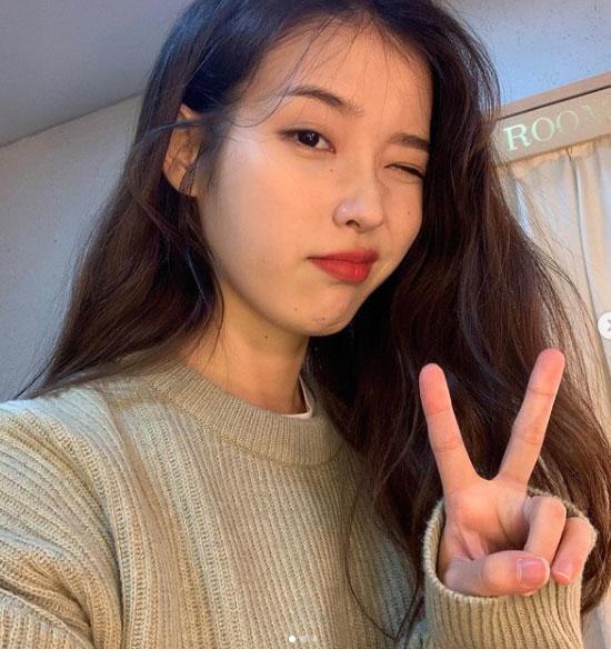 カジュアルなセーターを着た女性がピースサインをしている様子