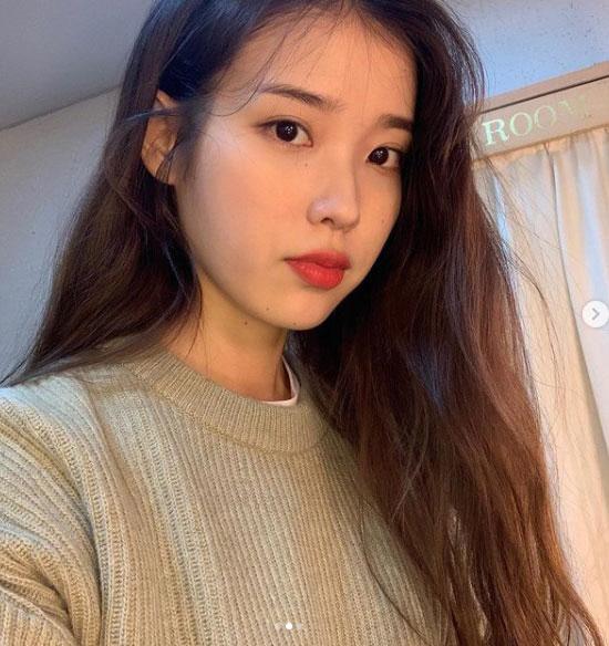 カジュアルなセーターを着た女性が明るい背景の室内にいる様子