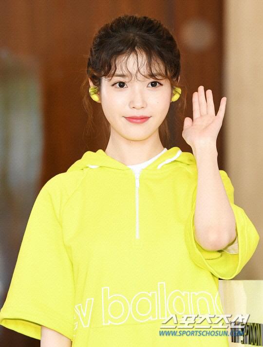 スパーツカジュアルな服を着た女性が片手を挙げている様子