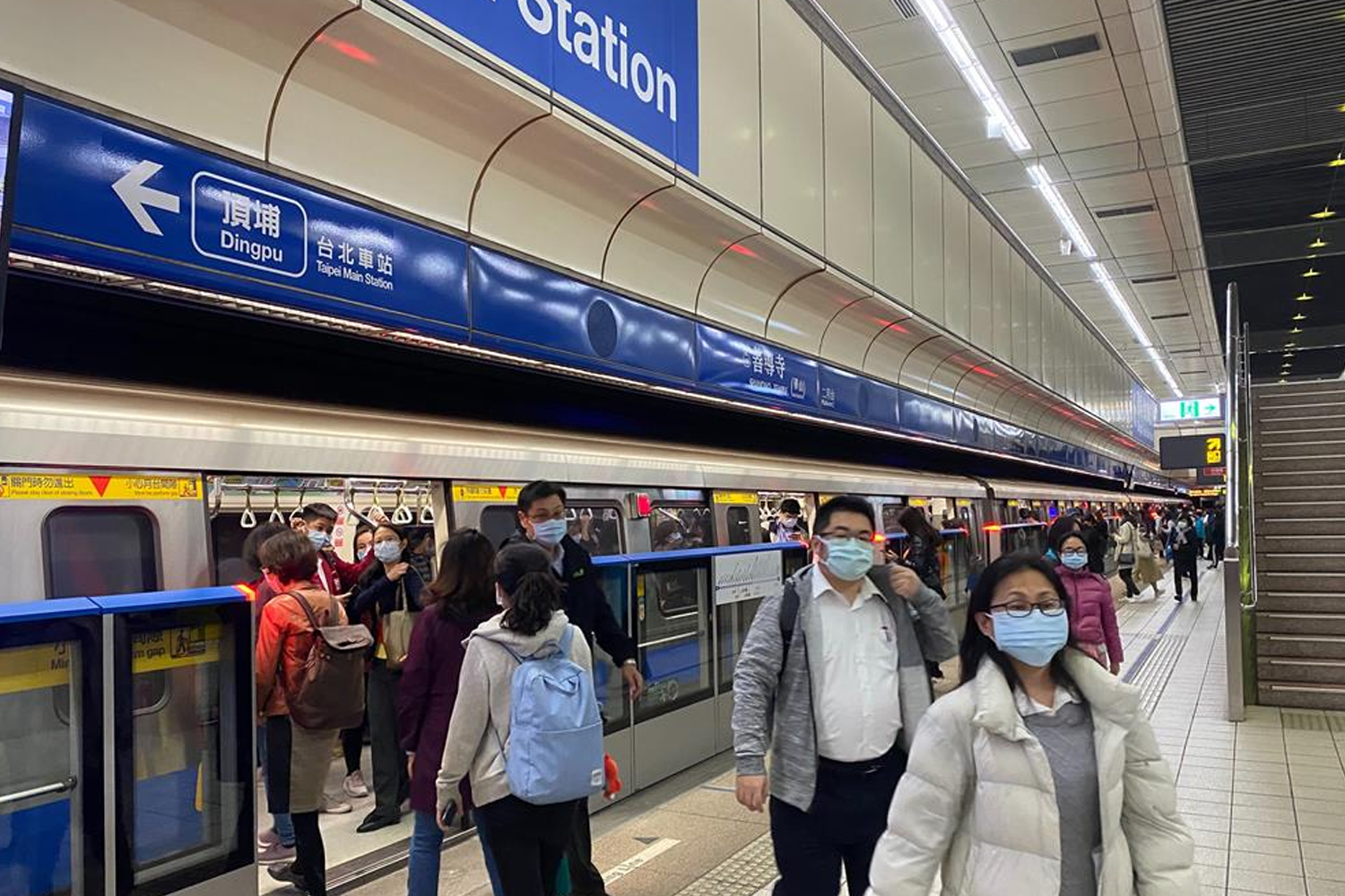 搭乘台北捷运的乘客，人人佩戴口罩，遵守防疫措施。