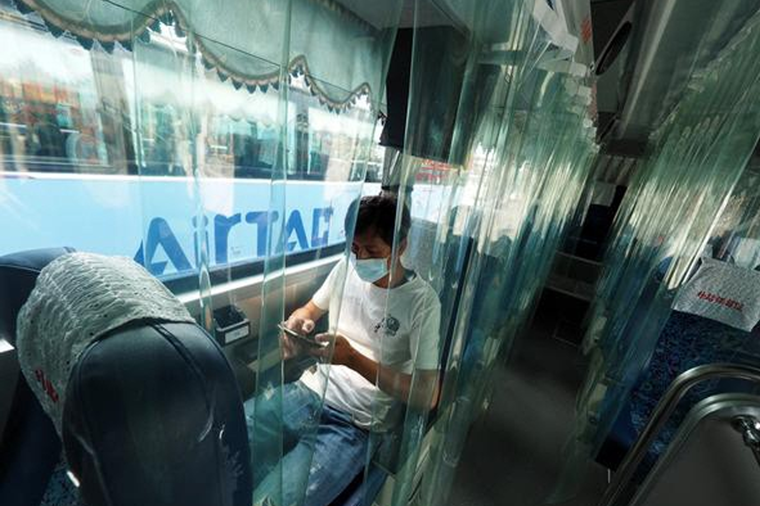 乘客在公车上通过透明隔板进行隔离，以减少疫情传播风险。