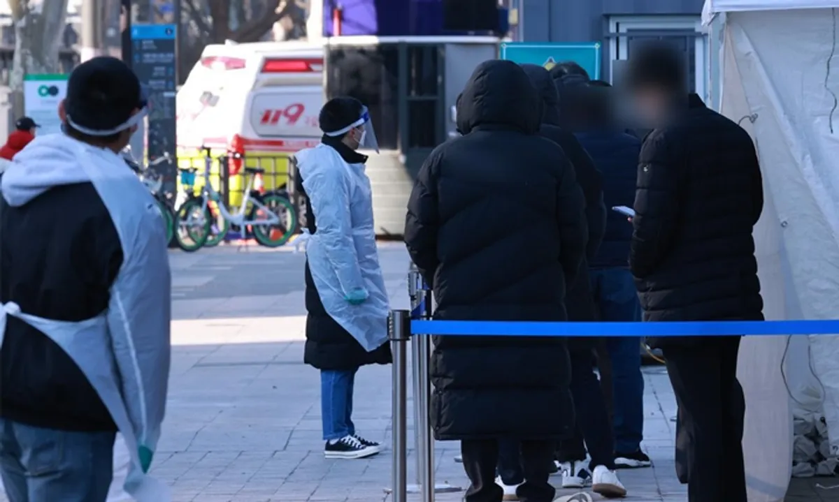 香港疫情下，市民在緊急情況下站立在街頭，遠處可以看見急救車，各人在等待進行新冠病毒檢測的模樣。