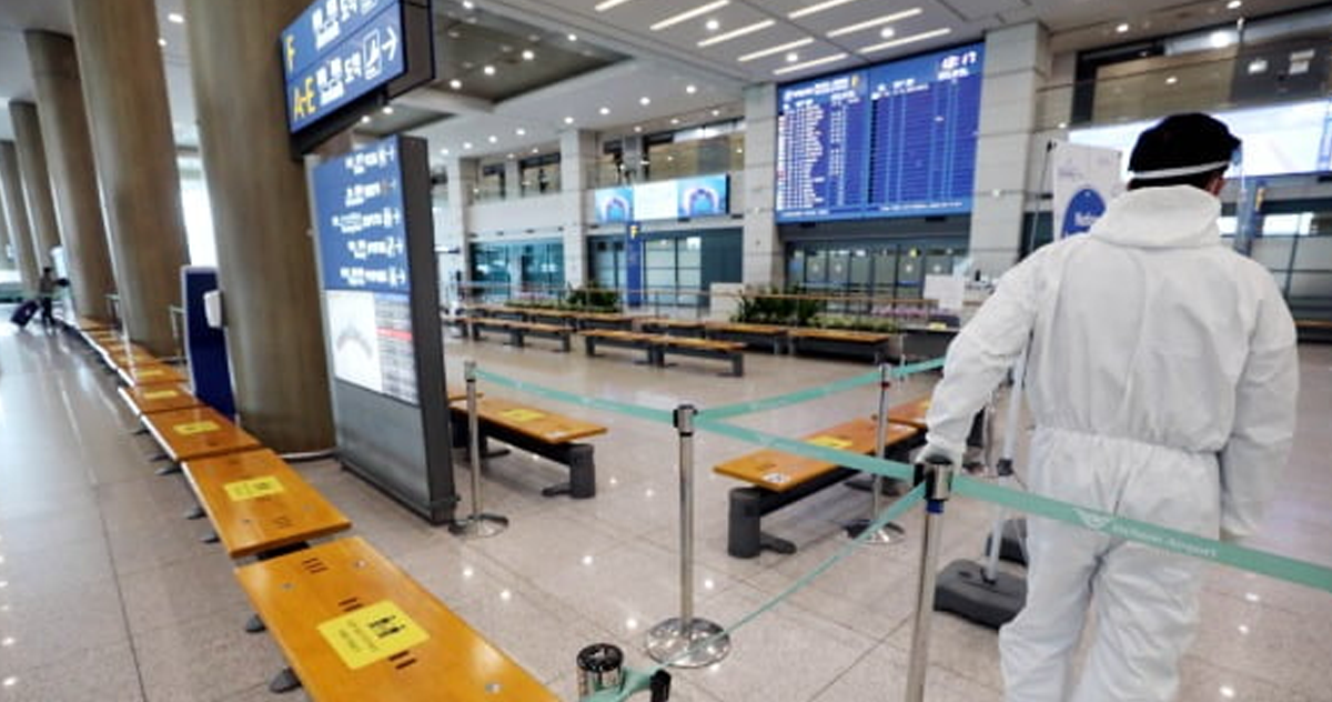 機場人員穿戴防護服，顯示出新冠疫情對國際旅行的影響與措施。