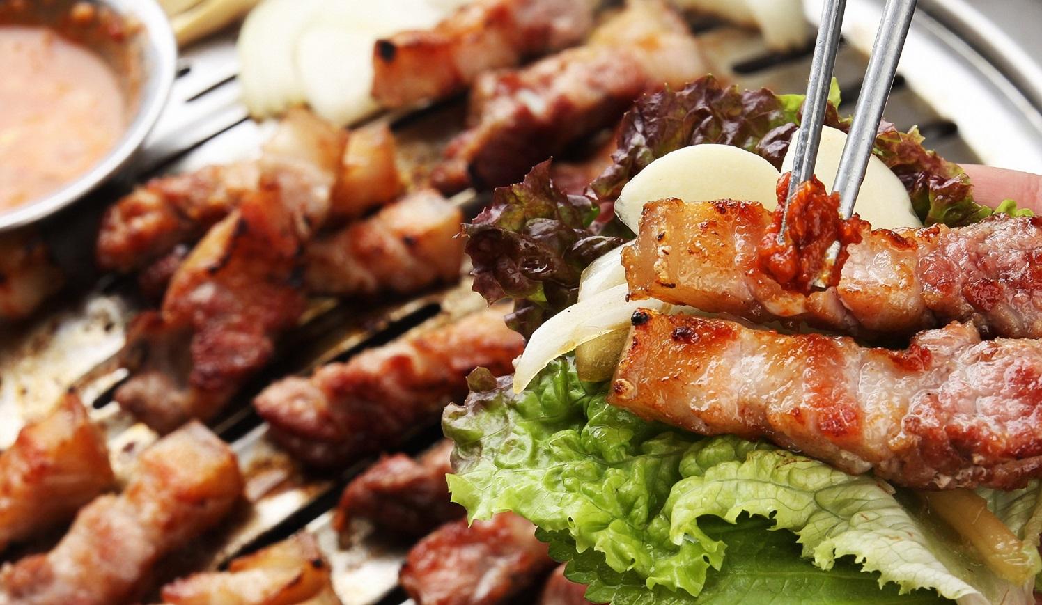 ภาพสตริตฟู้ดในเกาหลีที่มีผลไม้สด เช่น แอปเปิ้ลและส้มเรียงรายบนถนนในตลาดท้องถิ่น