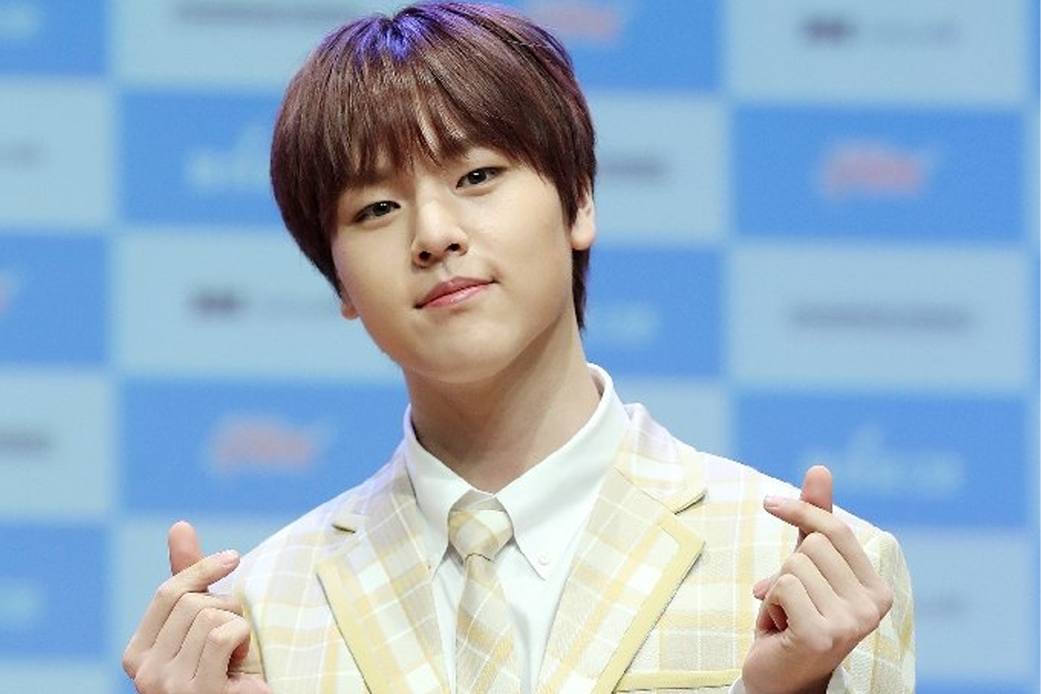 韓國男子組合BAE173的成員道賢，身穿淺黃色格子西服套裝，站在新聞發布會與媒體合影