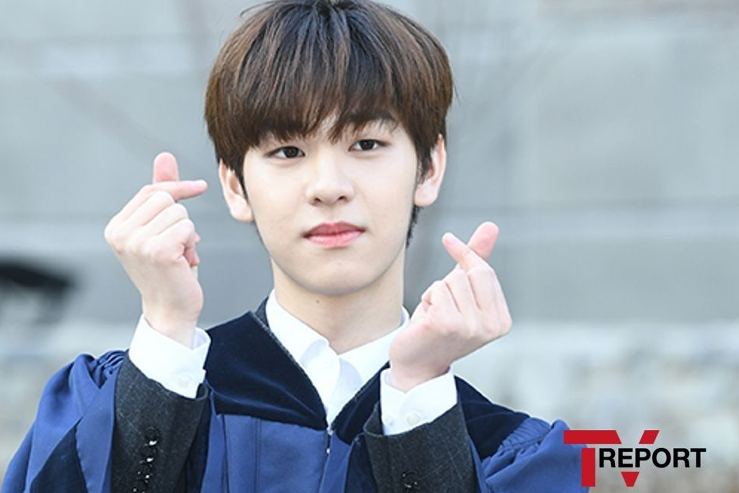 韓國男子組合DRIPPIN的成員東玧，身穿學生畢業服，背景為學校的灰色建築