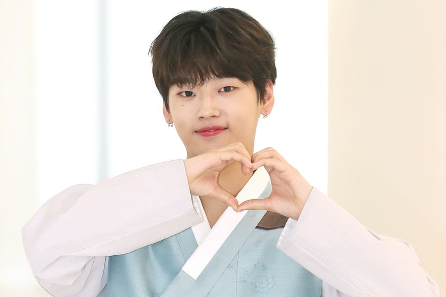 韓國男子組合WEi的成員錫華，學著韓服的樣式，背景是淡雅的室內裝潢