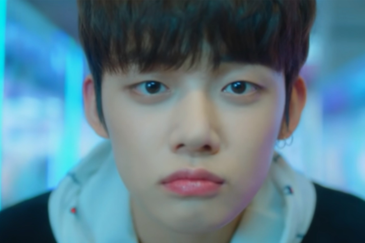 韓國男子組合TXT的成員YEONJUN，身穿連帽衫，背景是模糊的藍色燈光, 呈現科技未來感