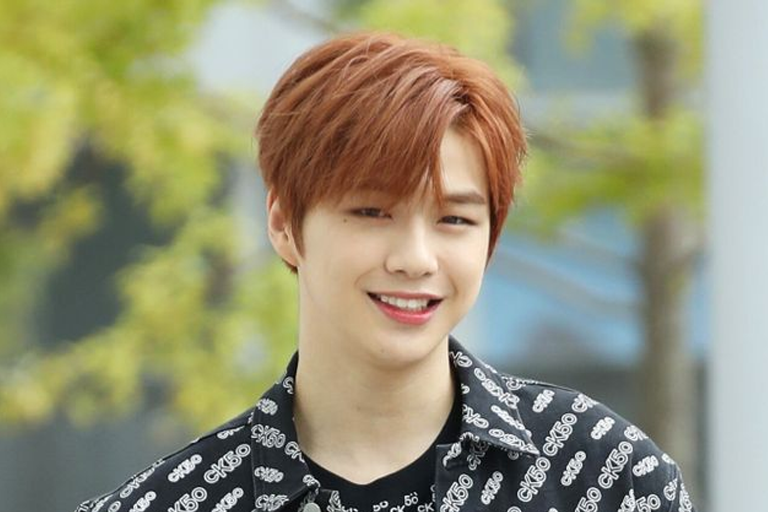 가을 배경에서 세련된 스타일의 남성이 검은 색 셔츠를 입고 있는 모습.