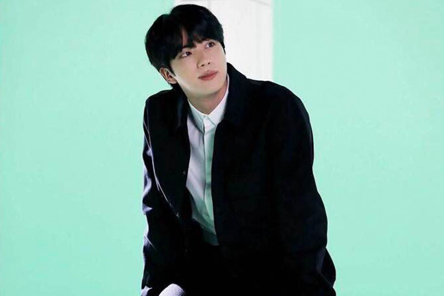 一名不知名韓國藝人在休息時，穿著深色服裝並拿著串燒。