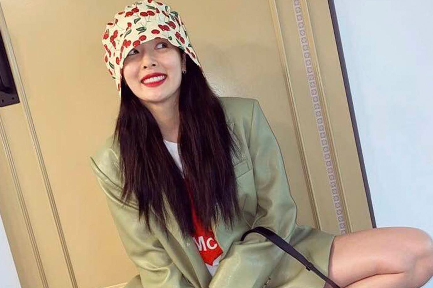 泫雅身穿白色連衣裙坐著，背景是充滿陽光的室外環境。