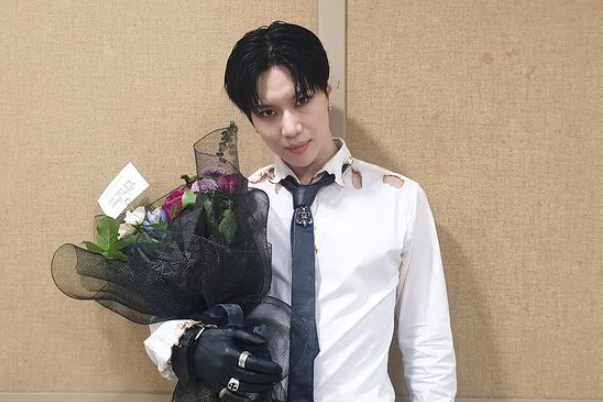 SHINeeのテミンが花束を持っている写真。