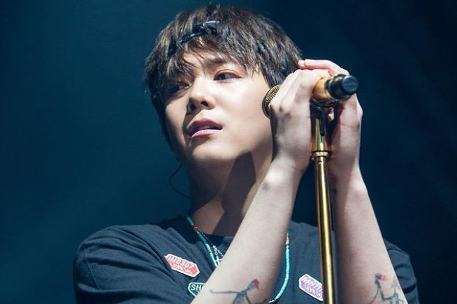 マイクを持ってライブパフォーマンスをする男性。