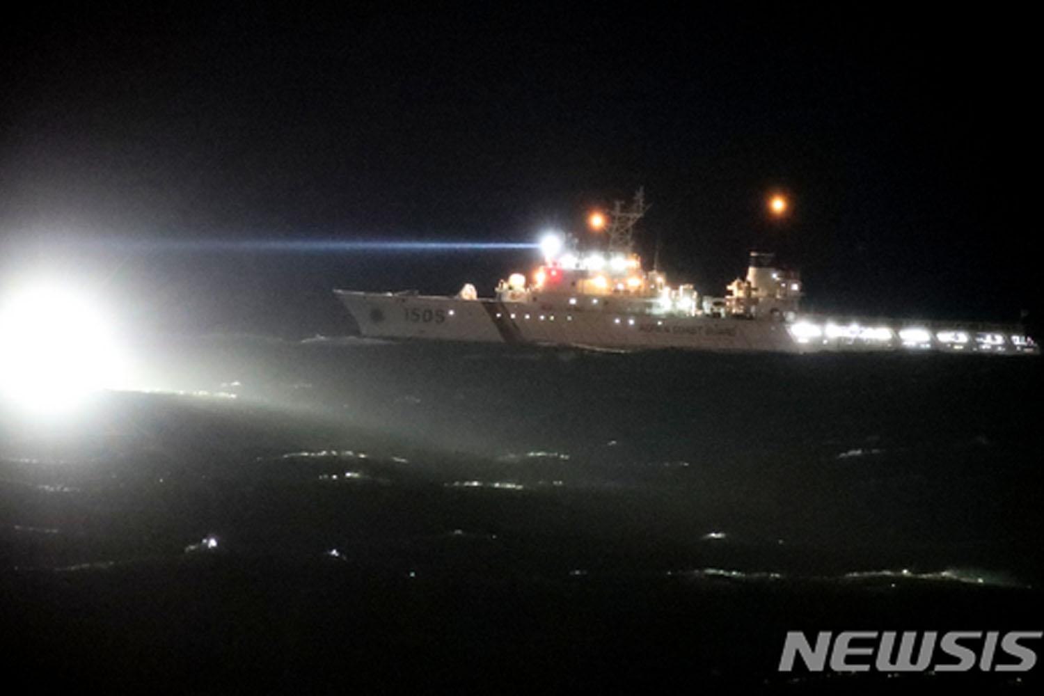 เรือลำหนึ่งของหน่วยยามฝั่งอาปาโน่กำลังเผชิญหน้ากับคลื่นสูงในช่วงกลางคืนเรืองแสงระยิบระยับในพื้นหลัง สถานการณ์นี้เกิดขึ้นหลังจากการเกิดอุบัติเหตุเรือประมงพลิกคว่ำที่เกาะเชจู โดยหน่วยยามฝั่งกำลังทำการปฏิบัติการณ์ช่วยเหลืออย่างต่อเนื่องในสภาวะที่ท้าทาย (ที่มาจาก Newsis) 