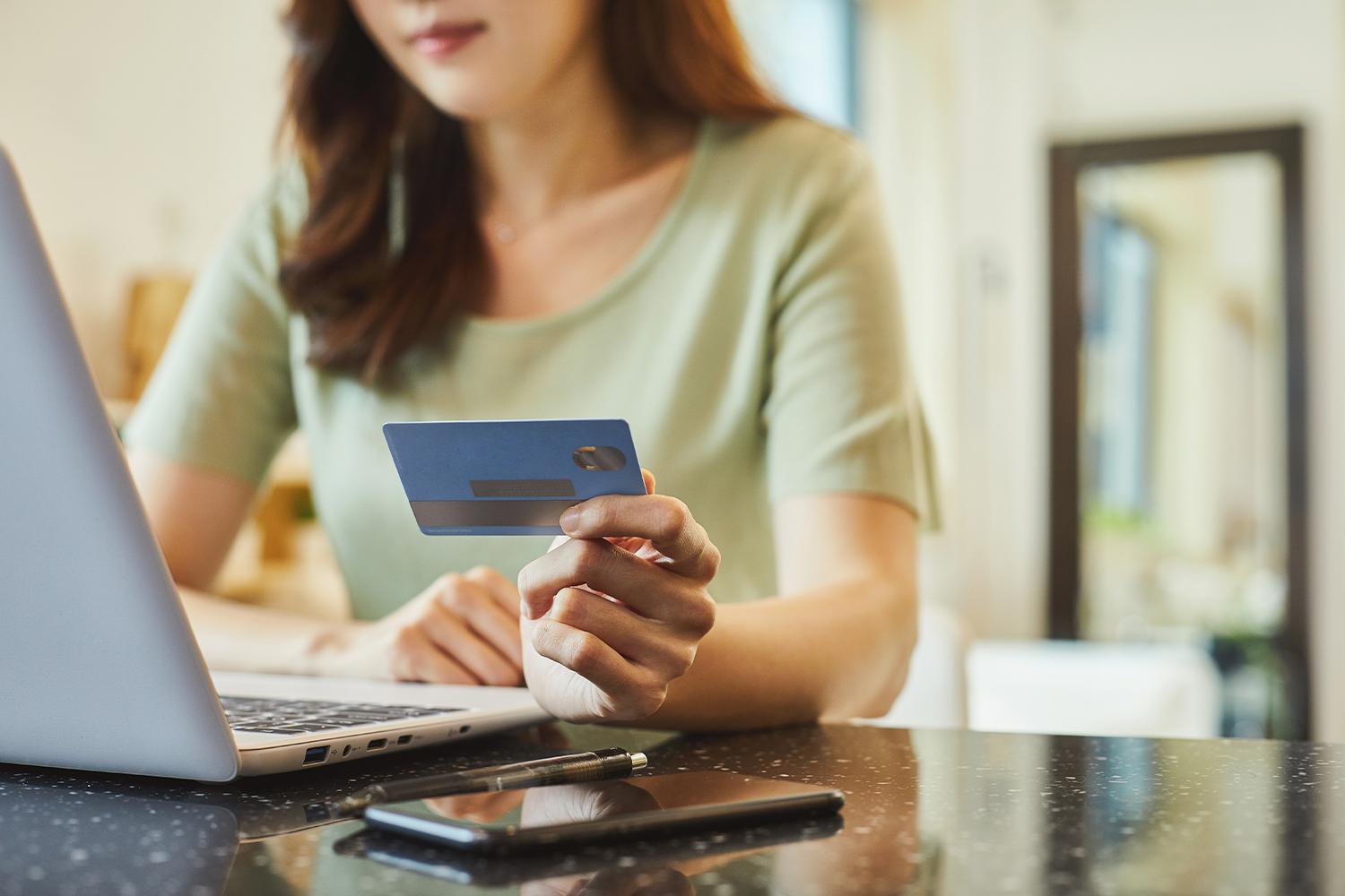 woman waiting to pay for online tickets with credit card in hand