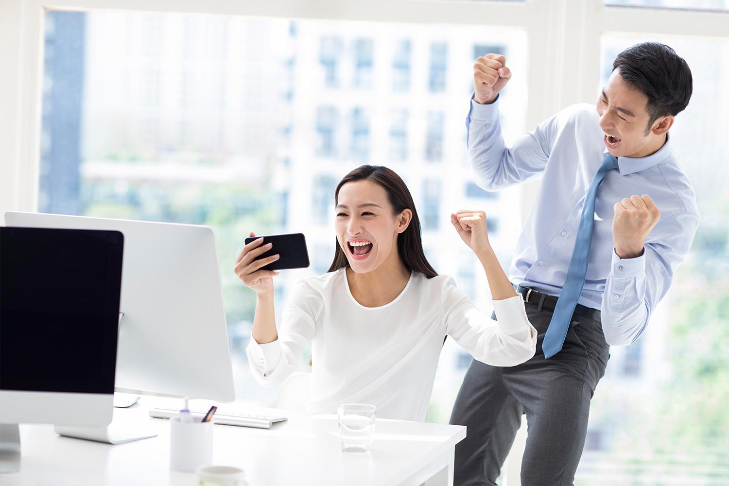 stock image of people excited over something on computer/phone screen