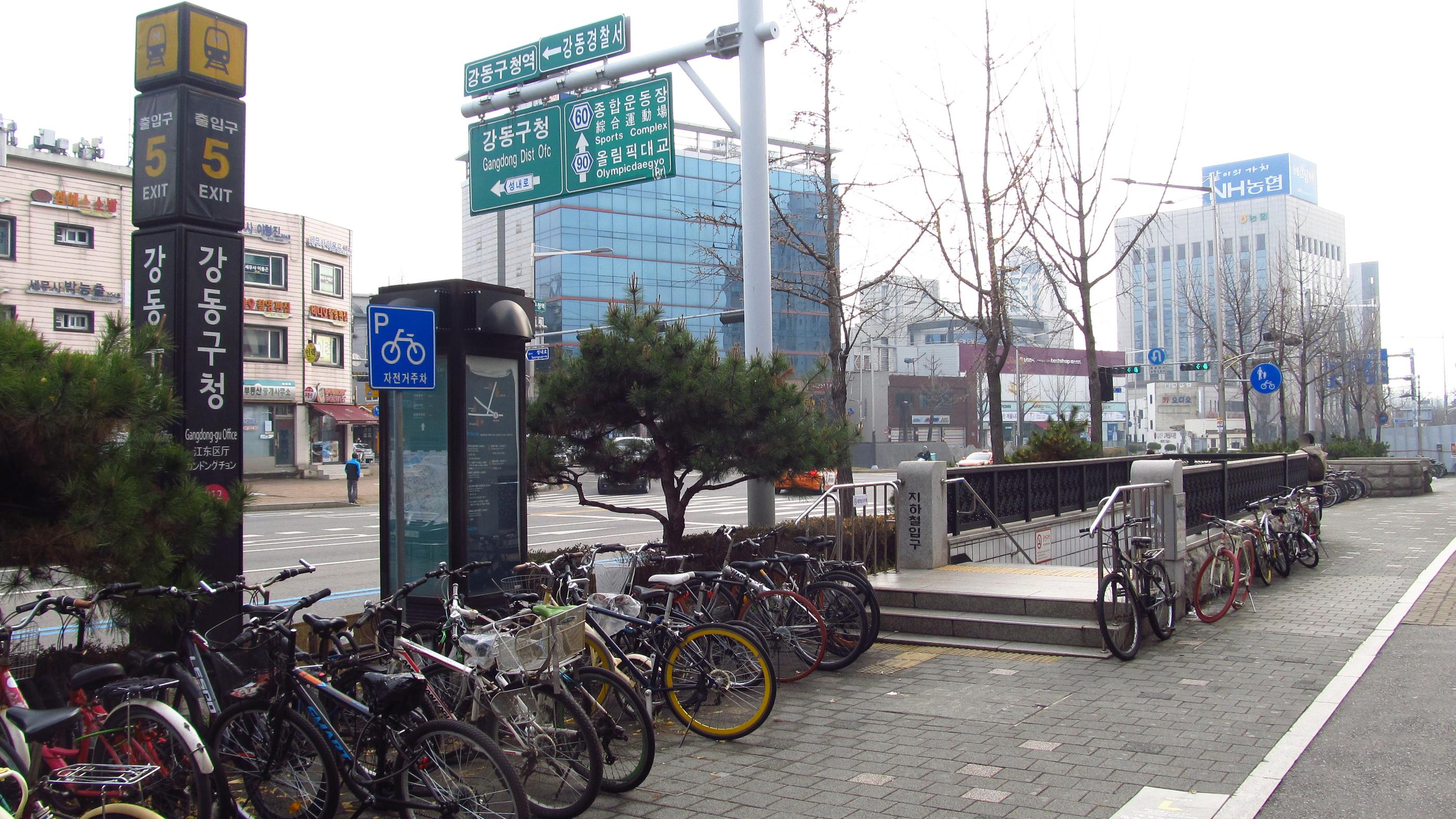 image of the outside of gangdong-gu office subway exit 5 with lots of parked bikes
